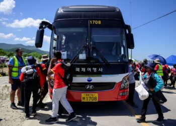 SEJUMLAH pengakap bersiap sedia menaiki bas untuk dipindahkan dari tapak perkhemahan ke lokasi yang ditentukan menjelang ketibaan Taufan Khanun. - AFP