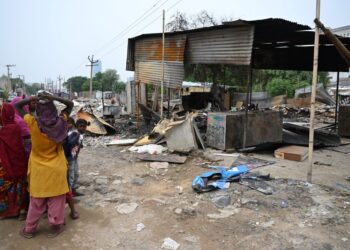 PENDUDUK berdiri di sebelah bangunan yang terbakar akibat rusuhan kaum di Gurugram di Haryana, India.-AFP