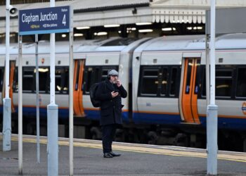 SEORANG lelaki menunggu kereta api di stesen Clapham Junction di selatan London. - AFP