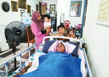 NOR Aziantie Azhar yang menghidap penyakit kulit kritikal terlantar sambil ditemani Muhammad Fatih Andika (berdiri, kanan) dan Liza Suriani Ab. Rahman (kiri) di rumah mereka di Gong Badak, Kuala Nerus, Terengganu. - UTUSAN/KAMALIZA KAMARUDDIN