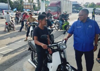 CALON BN kerusi DUN Sungai Dua, Shaik Hussein Mydin (kanan) menyantuni anak muda dalam jelajah kempen pada PRN di Sungai Lokan, Pulau Pinang semalam.