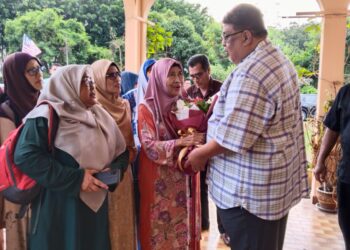 AB. RAUF Yusoh (kanan) menyampaikan jambangan bunga kepada Patimah Abu Hasan (empat dari kiri) pada program ziarah kasih di Batu Berendam, Melaka. - UTUSAN/MUHAMMAD SHAHIZAM TAZALI