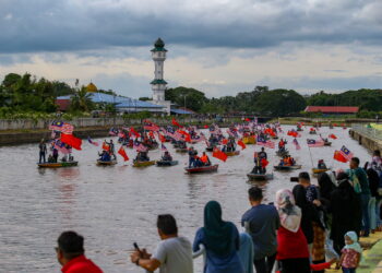 PESERTA menaiki bot sambil membawa Jalur Gemilang ketika menelusuri Sungai Kedah sempena sambutan Hari Kebangsaan ke-66 di Alor Setar. -UTUSAN/SHAHIR NOORDIN