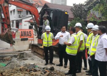 MOHAMAD FAZLI MOHAMAD SALLEH (dua dari kiri) meninjau kerja-kerja penggantian paip lama di Jalan Tan Hiok Nee, Johor Bahru.