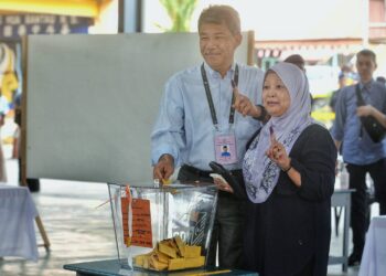 MOHAMAD Hasan dan isteri, Raja Salbiah Tengku Nujumudin menunjukkan jari yang telah dicelup dakwat di pusat mengundi SRJK Cina Chung Hua, Rantau, Seremban hari ini.-UTUSAN/MOHD. SHAHJEHAN MAAMIN.