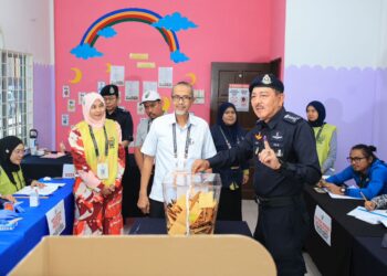 MUHAMAD Zaki Harun (kanan) semasa melaksanakan tanggungjawab sebagai pengundi pada hari mengundi awal sempena Pilihan Raya Negeri Dewan Undangan Negeri (DUN) Kota Lama di Pusat Mengundi Awal N09 Kota Lama, Ibu Pejabat Polis Kontinjen Kelantan (IPK), Kota Bharu, Kelantan hari ini-KAMARUL BISMI KAMARUZAMAN