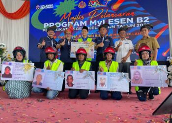 HASBI Habibollah (berdiri, dua dari kiri) bersama sebahagian penerima manfaat Program MyLesen B2 peringkat Kelantan di Dewan Tok Tangok, PPD Bachok, Kelantan, hari ini. UTUSAN/TOREK SULONG