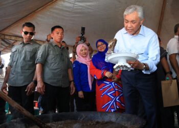 AHMAD Zahid Hamidi (kanan) meletakkan bubur asyura ke dalam mangkuk semasa Program Pemimpin bersama Masyarakat Perumahan Nelayan Tok Bali di Taman Perumahan Nelayan Tok Bali, Pasir Puteh, Kelantan-UTUSAN/KAMARUL BISMI KAMARUZAMAN