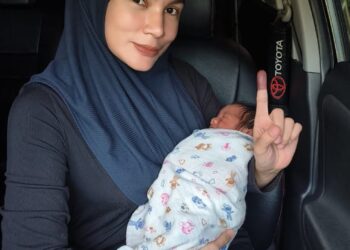 HAYATUL Ghazali memangku bayinya sambil menunjukkan jarinya telunjuk yang dicelup dakwat sejurus selesai mengundi di SK Sultan Ismail 4, di Kota Bharu, Kelantan hari ini.