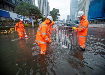 PEKERJA keselamatan memeriksa keadaan jalan yang dinaiki banjir di Shenzhen, wilayah Guangdong, China. - AFP