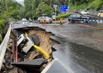 SEBUAH kenderaan rosak selepas jatuh ke dalam jalan mendap akibat hujan lebat di Hong Kong. - AFP