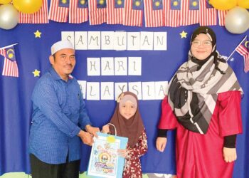 ZAKARIA Ahmad menyampaikan hadiah kepada salah seorang murid yang memenangi pertandingan mewarna sempena sambutan Hari Kebangsaan dan Hari Malaysia baru-baru ini.