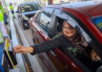 Kakitangan Besraya (M) Sdn Bhd, Azlyana Azmi, 33, menggunakan kad debit sebagai alternatif baru untuk membayar tol selepas Pelancaran Pelaksanaan Sistem Kutipan Tol Secara Pembayaran Terbuka (SPT) di Plaza Tol Loke Yew (arah timur). - Utusan / Saddam Yusoff