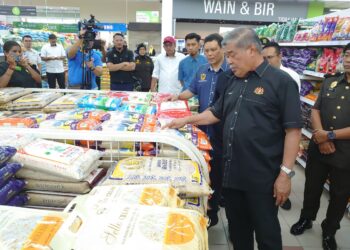 MOHAMAD SABU (kanan) meninjau bekalan beras tempatan di sebuah pasar raya di Tampoi, Johor Bahru.