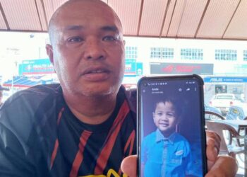 KARIM MOHD. SAID menunjukkan gambar Muhammad Zafran Iskandar yang dijaganya di Bandar Utama, Segamat