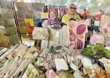 SURAIZAM Saad (kanan) dan Suraini menunjukkan pelbagai jenis produk batik cetakan eko yang menggunakan tekapan serta tempelan daun pada Festival Kraftangan Utara (FKU) 2023 di Perbadanan Kemajuan Kraftangan Malaysia Cawangan Perlis, semalam. - UTUSAN/JAMLIAH ABDULLAH