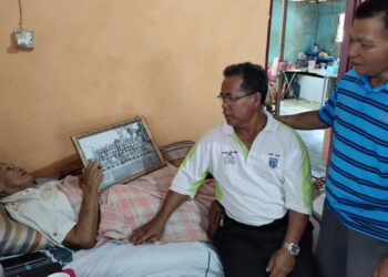 JANTAN Harun (kiri) menunjukkan gambar kenangannya ketika bertugas dalam pasukan Home Guard ketika ditemui di rumahnya di Kampung Paya Lebar, Air Kuning Selatan, Tampin, semalam.-UTUSAN/NOR AINNA HAMZAH.