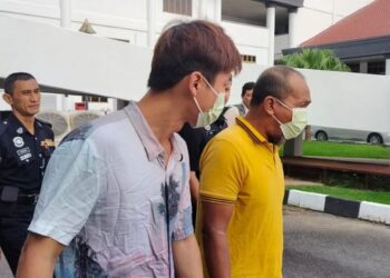 LOH Ker Chun (kiri) dibawa ke Mahkamah Majistret dengan diiringi polis bagi berdepan pertuduhan memiliki 25 keping wang RM100 palsu di Alor Setar.