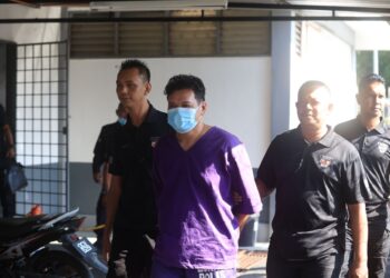 TERTUDUH (tengah) diiringi polis semasa tiba di Mahkamah Majistret Tanah Merah, Kelantan hari ini-UTUSAN/KAMARUL BISMI KAMARUZAMAN.