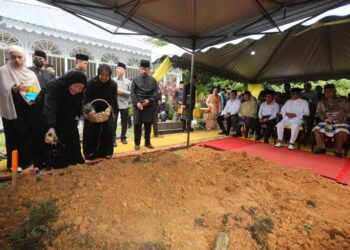 ISTERI Allahyarham Abdullah Fadzil Che Wan, Datin Seri Che Ezatul Hamsiah Hussin (kiri) menabur bunga di pusara suaminya pada pengebumian di  Tanah Perkuburan Islam Masjid Panglima Kinta di Ipoh hari ini. - UTUSAN