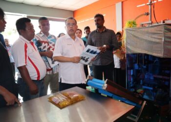 ABDUL Fattah  Abdullah (tengah) merasmikan kilang pembungkusan minyak masak usaha sama anggota Koperasi FELDA Trolak Utara di Sungkai hari ini. - UTUSAN