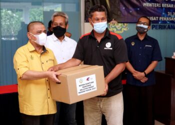 SAARANI Mohamad (kiri) menyampaikan sumbangan kotak makanan kepada nelayan darat pada program di Lenggong. - UTUSAN/ZULFACHRI ZULKIFLI