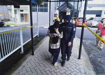 NURUL Wahida Mohd. Adnan (kiri) dibawa anggota polis selepas berdepan pertuduhan mengedar dadah bersama suaminya di Mahkamah Majistret Sungai Petani.