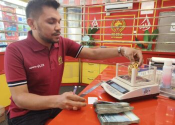 MURTADHATUMIZI Mustahapa menimbang berat gelang emas yang dijual di premisnya di Kota Bharu, Kelantan semalam. – UTUSAN/YATIMIN ABDULLAH