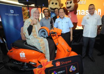 AHMAD MASLAN menyampaikan hadiah utama berupa skuter kepada pemenang Goncang dan Menang Shopee, Ayu Masitah Norhamizan (kiri) sempena Majlis Penutupan Karnival Celik Kewangan Johor di AEON Mall, Kulai.