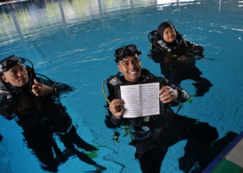 AHMAD Fudhail Ahmad Kenedi (tengah) bersama dua pembantu penyelam menunjukkan esei yang ditulis pada kedalaman lima meter selama sejam 34 minit sehingga diiktiraf sebagai pemegang rekod pertama oleh MBOR di Pusat Akuatik Kedah, Gunung Keriang di Alor Setar. - UTUSAN/ SHAHIR NOORDIN