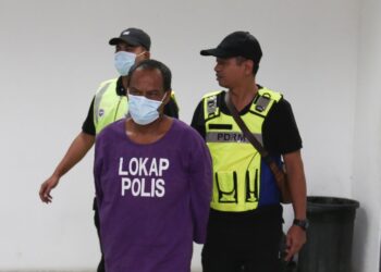 TERTUDUH (tengah) diringi oleh anggota polis semasa menghadiri perbicaraan di Mahkamah Seksyen Kota Bharu,Kelantan hari ini-UTUSAN/KAMARUL BISMI KAMARUZAMAN