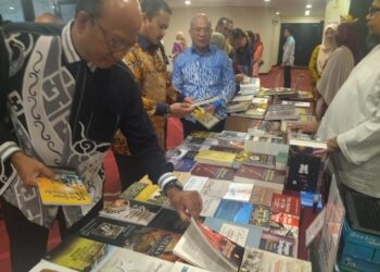 AZMAN Mohd. Yusof (kiri) melihat buku yang dipamerkan pada program Bicara Bahasa Kolokial: Melestarikan Keberdayaan Bahasa Komuniti 'Moh Labun Loghat Perak' di Ipoh, Perak hari ini. - UTUSAN/FADZIL ZAINOL