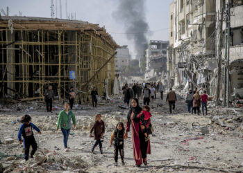 PENDUDUK Palestin berjalan melalui bangunan yang runtuh akibat bedilan udara tentera Zionis di Gaza City. - AFP