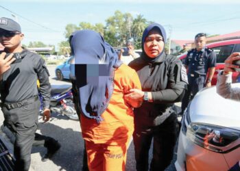 SEORANG usahawan tudung (tengah) yang dituduh membunuh rakan kongsinya dibawa masuk ke Mahkamah Majistret Marang, di Marang, Terengganu, semalam. - UTUSAN/PUQTRA HAIRRY ROSLI