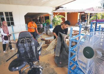 MUHAMMAD Akmal Danial Azman (kanan) bersama adik-beradiknya membersihkan barangan rumah selepas dilanda banjir di Kampung Cemperai, Dengkil, Selangor. - UTUSAN/FAISOL MUSTAFA