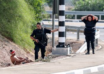 ANGGOTA polis Israel memerhatikan seorang tahanan Palestin yang ditutup matanya di Ashkelon yang bersempadan dengan Semenanjung Gaza pada 8 Oktober lalu. - AFP