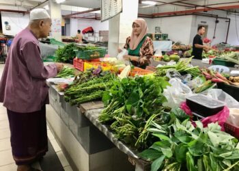 ASMALIZA Ismail melayan pelanggan yang membeli sayur di gerainya di Pasar Berek 12, Kota Bharu, Kelantan semalam. – UTUSAN/ ROSLIZA MOHAMED