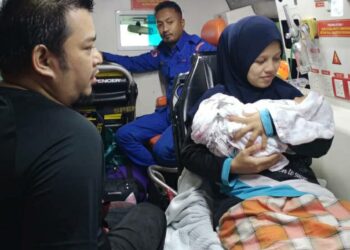 ANGGOTA APM membantu membawa bayi perempuan berusia empat hari yang mengidap penyakit kuning dari Kampung Kasar ke Klinik Kesihatan Seri Langkap di Setiu, hari ini.