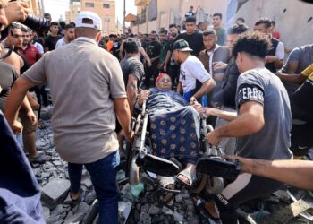 Orang ramai memindahkan wanita yang berkerusi roda dari kediamannya yang musnah akibat serangan udara tentera Israel di Khan Yunis, selatan Semenanjung Gaza, semalam. -AFP