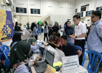 LEE TING HAN  (dua dari kanan) melihat proses pendaftaran pekerja di kaunter Perkeso selepas merasmikan Karnival Kerjaya Myfuturejobs di Dewan Majlis Perbandaran Kluang (MPK) Paloh, Kluang.