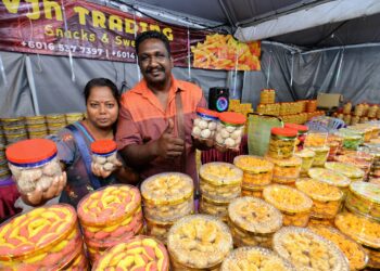 N. GOPINATHAN (kanan) dan isterinya, K. Kalaiarasi menunjukkan kuih tradisional masyarakat India yang dijual di gerainya yang terletak di Karnival Deepavali Negeri Sembilan 2023 di Taman AST, Seremban.-UTUSAN/MOHD. SHAHJEHAN MAAMIN.