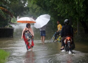 SEBAHAGIAN penduduk meredah banjir dengan membawa barangan keperluan untuk ke tempat yang lebih selamat selepas kawasan berkenaan dinaiki air di Kampung Gong Tok Nasek, Kuala Terengganu, hari ini. - UTUSAN/PUQTRA HAIRRY