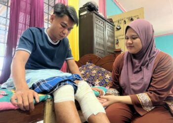 MUHAMMAD Zulhilmi Mokhtar (kiri) cedera di bahagian muka, badan dan kaki selepas motosikal yang ditungganginya dipercayai merempuh seekor harimau belang yang tiba-tiba keluar dari kawasan semak di Jalan Gua Musang-Jeli, Gua Musang, Kelantan, semalam. UTUSAN/AIMUNI TUAN LAH