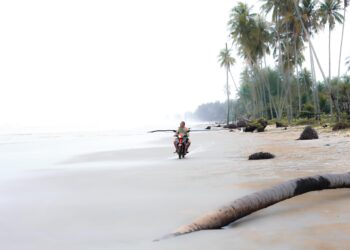 SEORANG penduduk menunggang motosikal sambil meninjau keadaan ombak di Pantai Damak, Bachok, Kelantan hari ini-UTUSAN/KAMARUL BISMI KAMARUZAMAN.