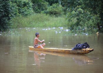 SEORANG penduduk menggunakan perahu selepas kawasan rumahnya ditenggelami banjir di Kampung Tersang, Rantau Panjang, Kelantan.-UTUSAN/KAMARUL BISMI KAMARUZAMAN