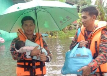 ANGGOTA Bomba dan Penyelamat Balai Bachok memangku seorang bayi berusia 19 hari untuk dibawa ke PPS SK Jelawat selepas rumahnya ditenggelami banjir di Kampung Dusun Durian, Bekelam, Bachok, Kelantan-IHSAN BOMBA BACHOK.