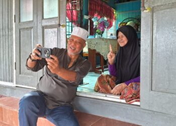 RAJA Mohamed Affandi Raja Mohamed Noor Raja berswafoto bersama seorang penduduk ketika berkempen di Kampung Pasir Gajah, Kemaman, hari ini. - UTUSAN/NIK NUR IZZATUL HAZWANI NIK ADNAN
