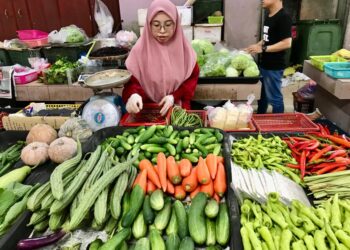 TASNIM Abdullah menyusun sayur yang dijualnya di Pasar Siti Khadijah Kota Bharu, Kelantan.- UTUSAN/ROSLIZA MOHAMED