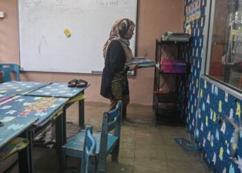 SEORANG guru mengemas buku di sebuah kelas yang dinaiki air di Sekolah Kebangsaan Wakaf Mempelam, Kuala Terengganu, semalam. - UTUSAN/PUQTRA HAIRRY ROSLI