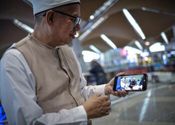 ZULKIFLI Mohamad Al-Bakri menunjukkan gambar penyerahan jam jenama Rolex kepada pemilik yang berjaya bidaan di KLIA . - UTUSAN/FAIZ ALIF ZUBIR